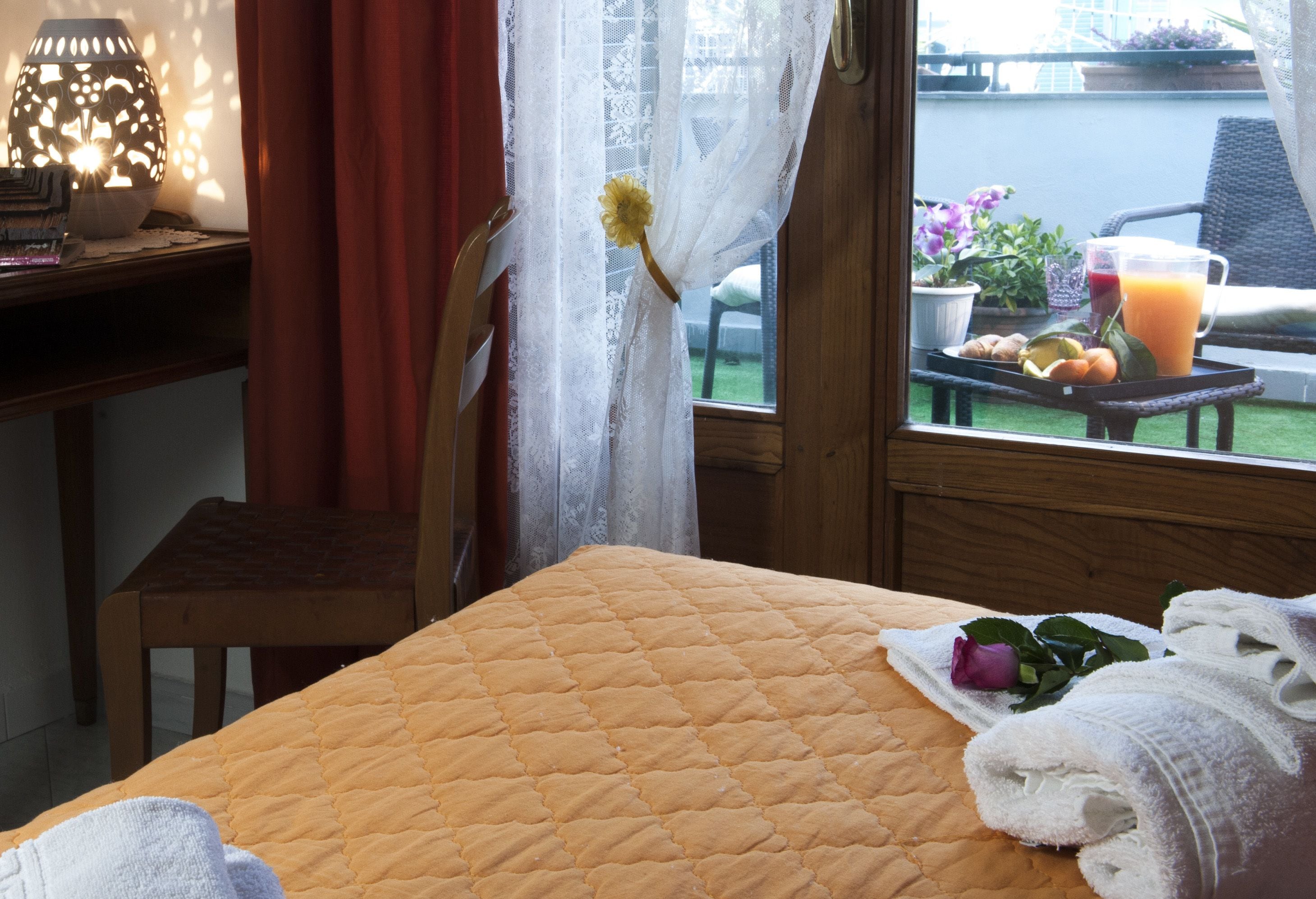 Een kamer met een bed, een raam met uitzicht op het omliggende landschap, een tafel met een dienblad vol eten en drinken, en een stoel.