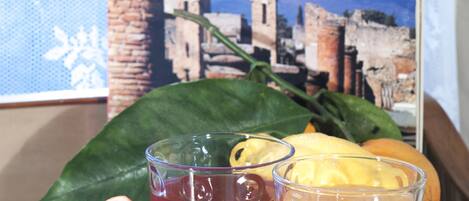 A book titled 'Guide à la Ville Archéologique Pompeii' with a backdrop of ancient ruins, a glass of orange juice, and a half-cut blood orange on a lace doily.