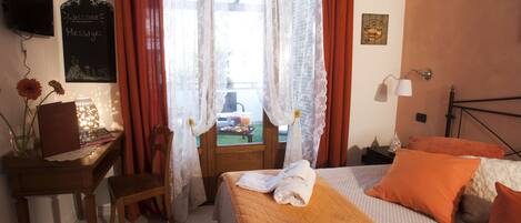 A bedroom with a bed, a desk, and a window with curtains.