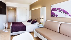 A modern hotel room with a bed, a sofa, a dining table with two glasses, and a wall-mounted TV. - Mariant (Sant Llorenc des Cardassar)