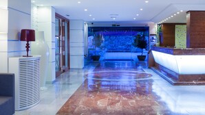 A modern hotel lobby with a reception desk, a seating area, and a large aquarium in the background. - Mariant (Sant Llorenc des Cardassar)