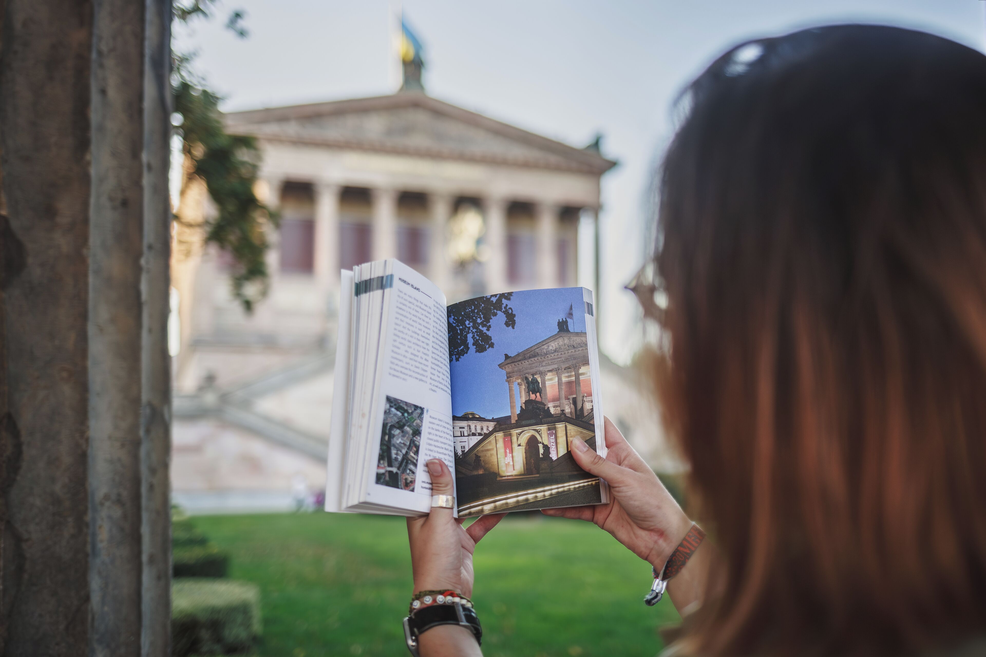 A person holding a book with a photograph of a classical building.