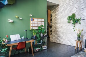 Un espacio de trabajo moderno con una pared verde, un escritorio de madera y una estantería.