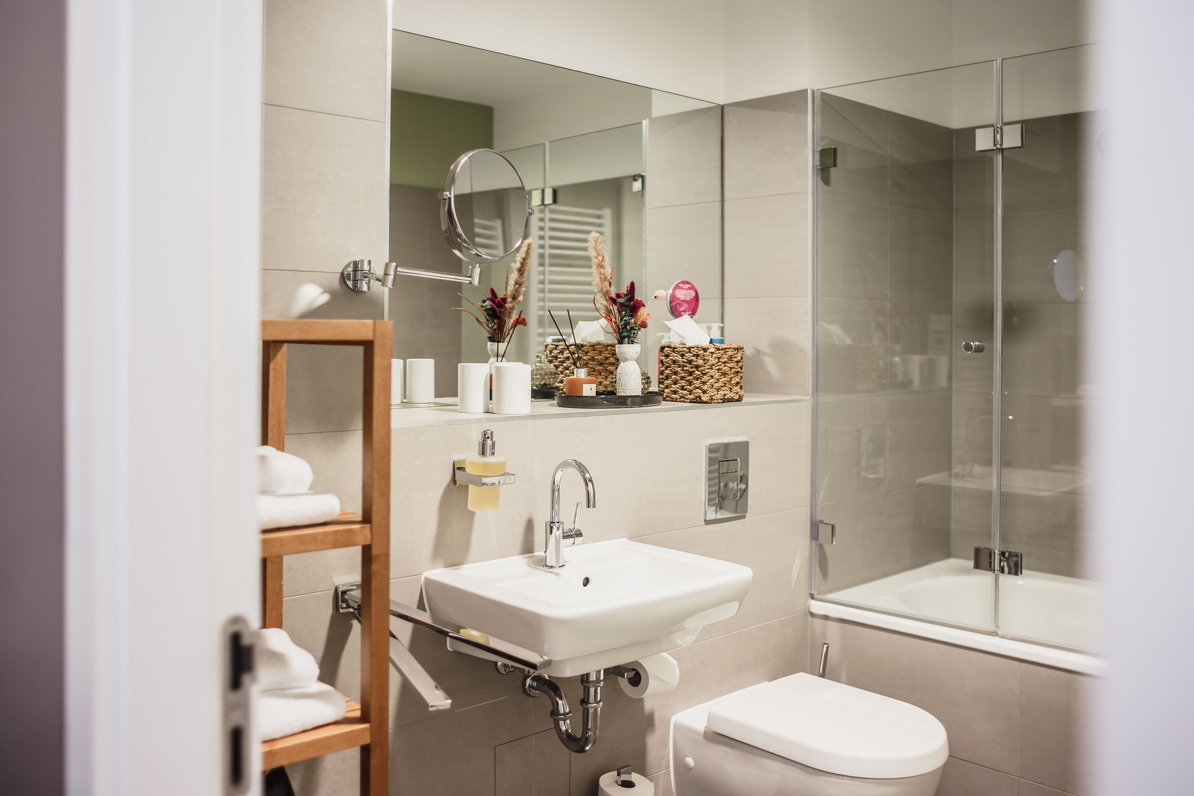 Un baño moderno con lavamanos, inodoro y ducha con mampara de vidrio.
