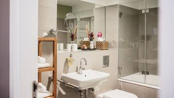 Un baño moderno con lavamanos, inodoro y ducha con mampara de vidrio.