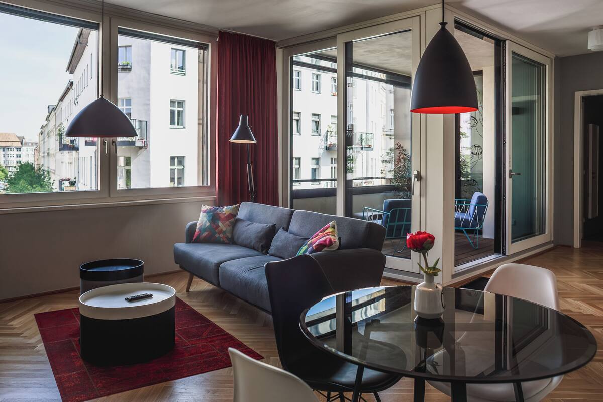 Ein modernes Wohnzimmer mit einer Couch, einem Glastisch und einem roten Teppich.