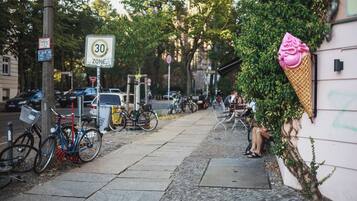 A street with parked bicycles, a speed limit sign, and a building with a large ice cream cone decoration.