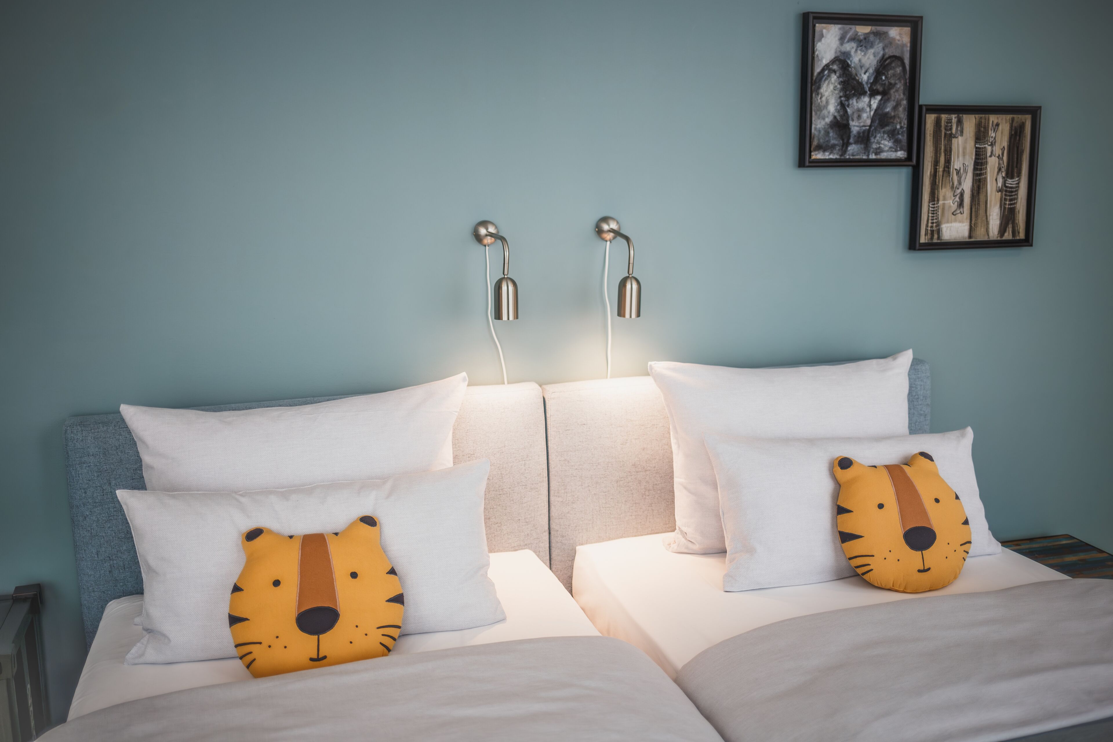 Habitació d'hotel amb dos llits, roba de llit blanca i una almoçada amb tema de tigre.
