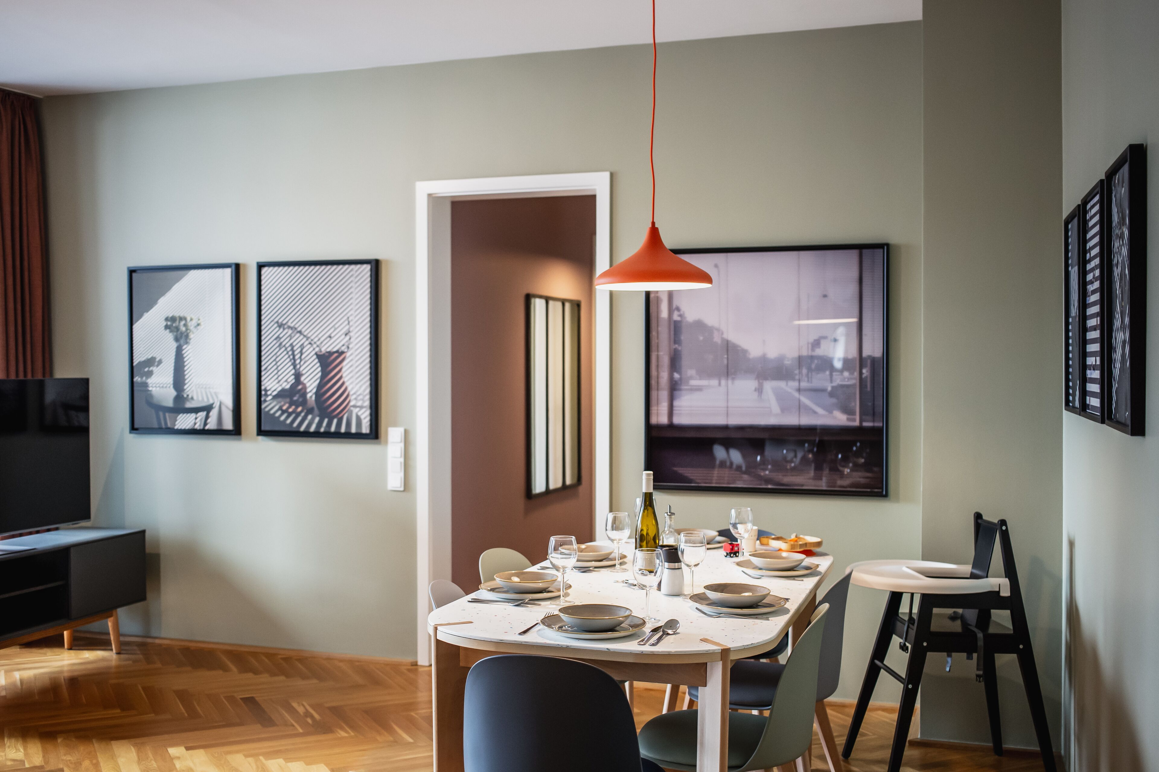 A dining area with a table set for four, a television, and framed artwork on the walls.