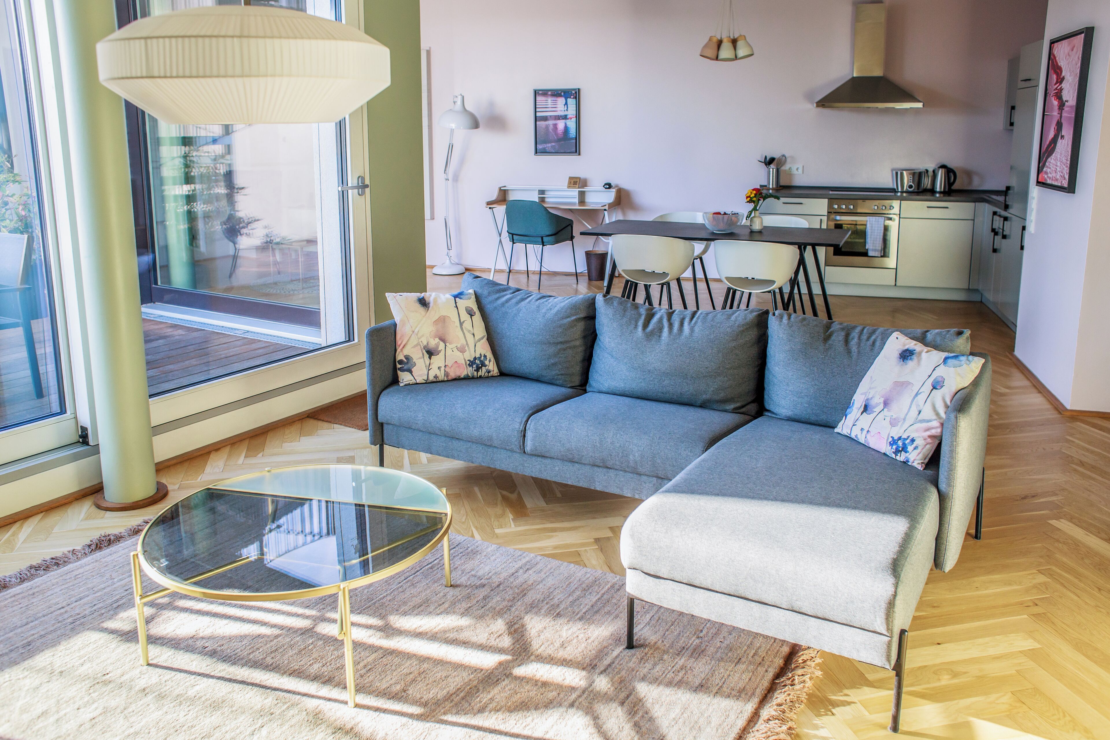 Una sala moderna con un sofá, una mesa de centro de vidrio y un comedor con sillas y una mesa.