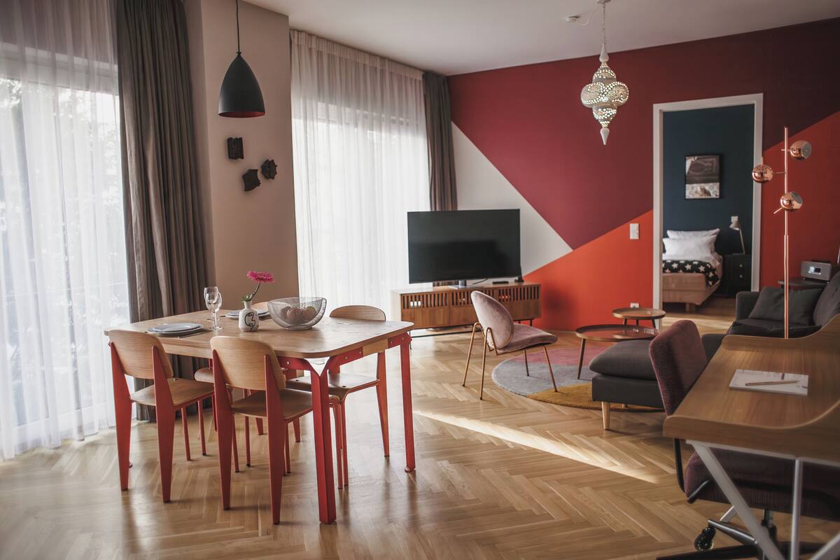 Ein modernes Wohnzimmer mit Essbereich, Fernseher und einem Bett.