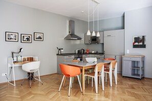 Cocina moderna con zona de comedor, que presenta un suelo con patrón de espiga, una isla central y un armario gris con un microondas encima.