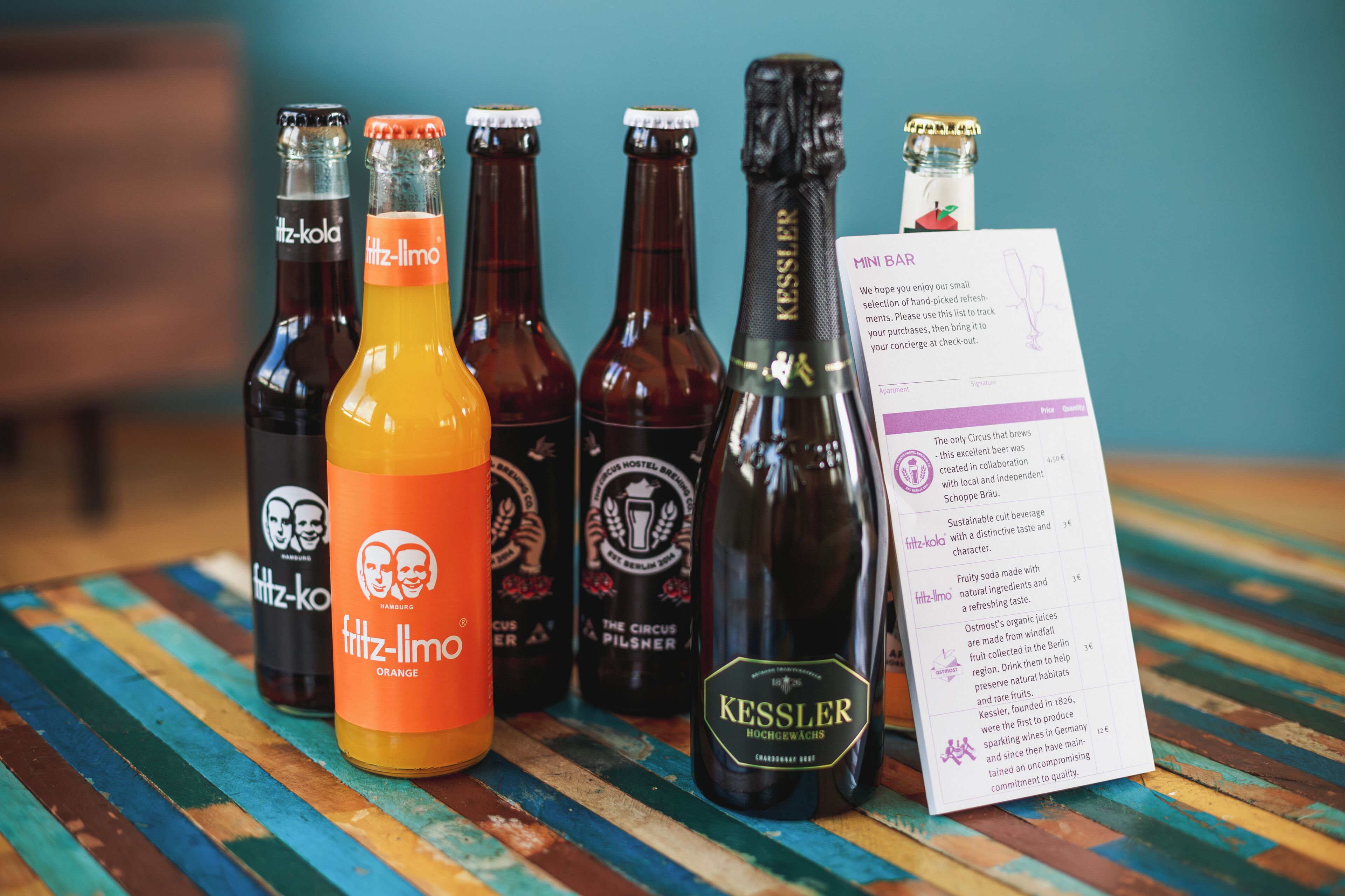 Varias botellas de cerveza sobre una superficie de madera con un mantel a rayas de colores.