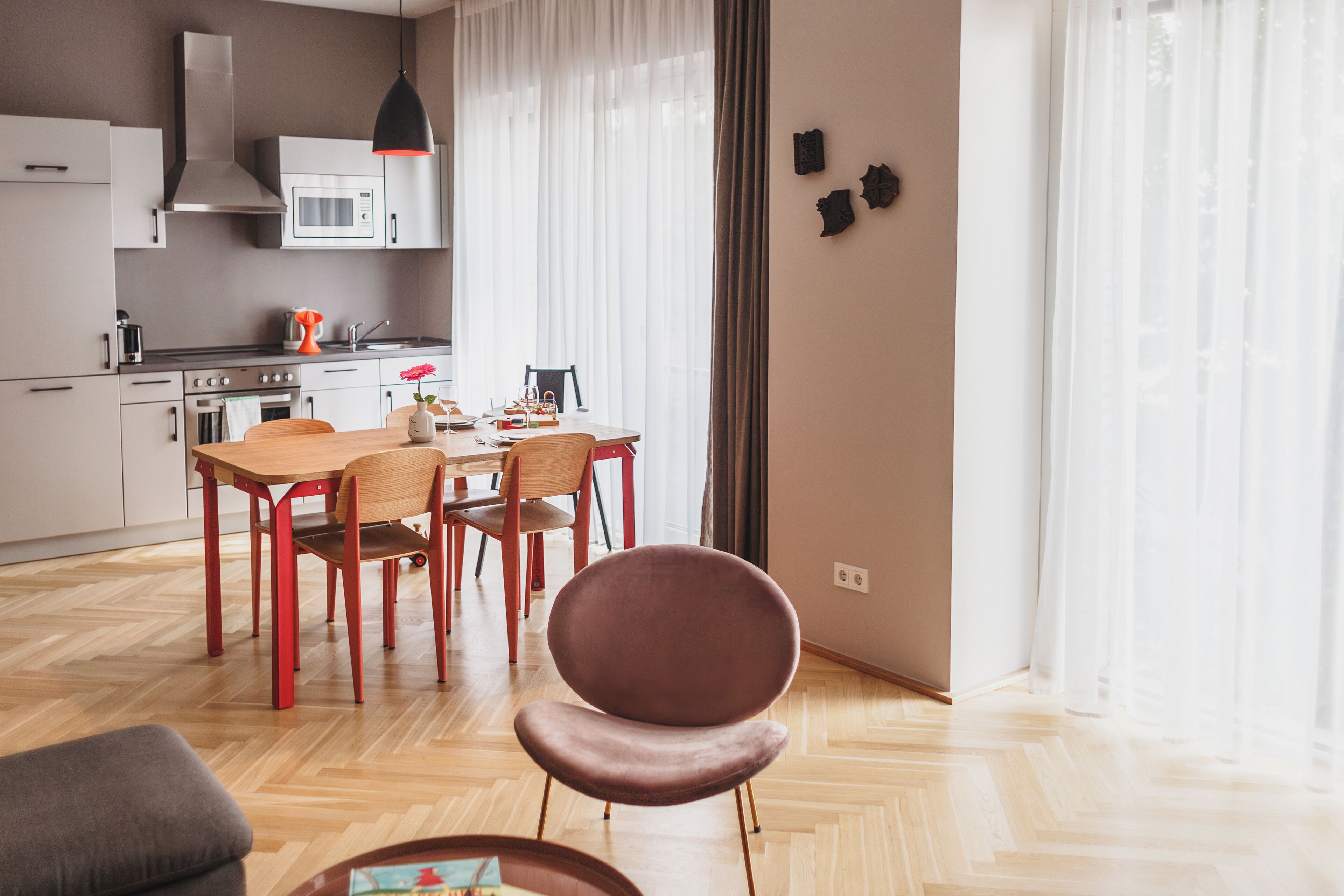 Una cocina moderna con comedor, suelo de madera y un amplio ventanal con cortinas.