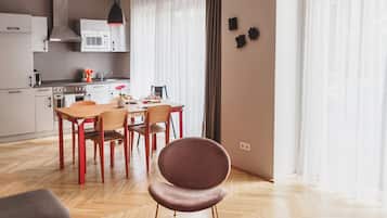 Una cocina moderna con comedor, suelo de madera y un amplio ventanal con cortinas.