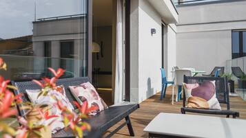 Un área de estar exterior moderna con un sofá, sillas y una mesa.