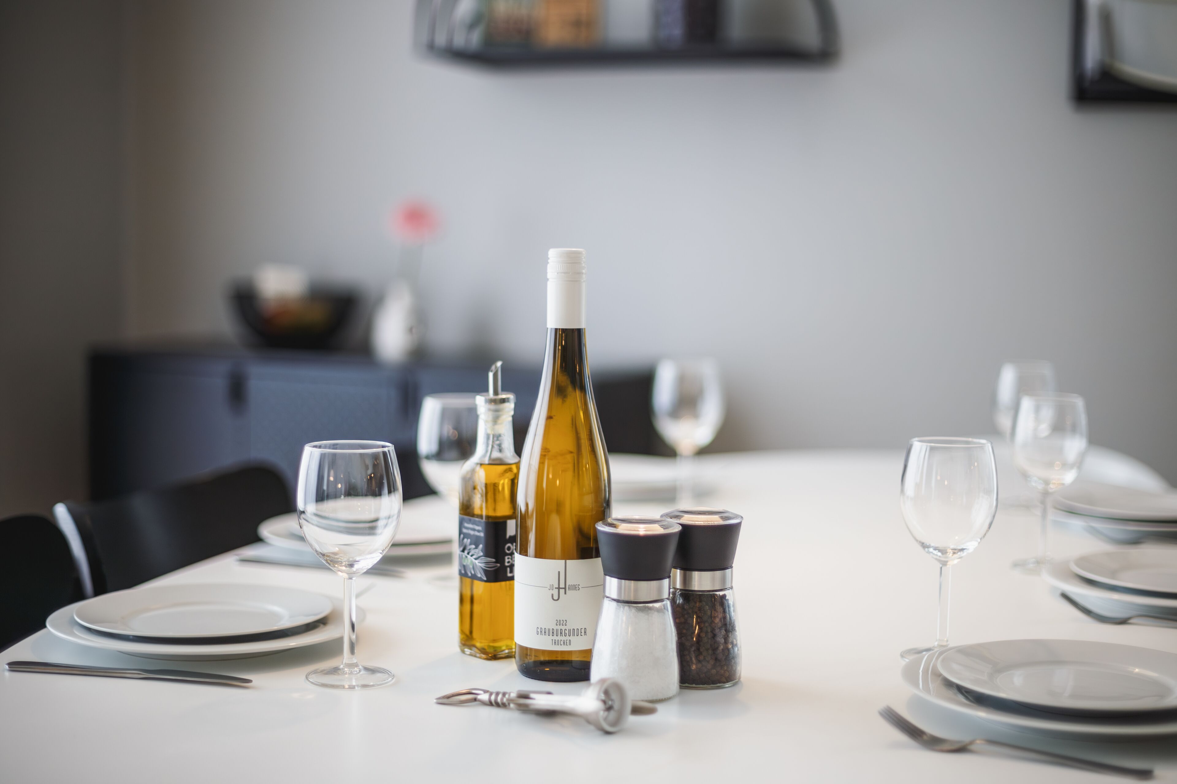 A dining table set with wine bottles, glasses, and salt and pepper shakers.
