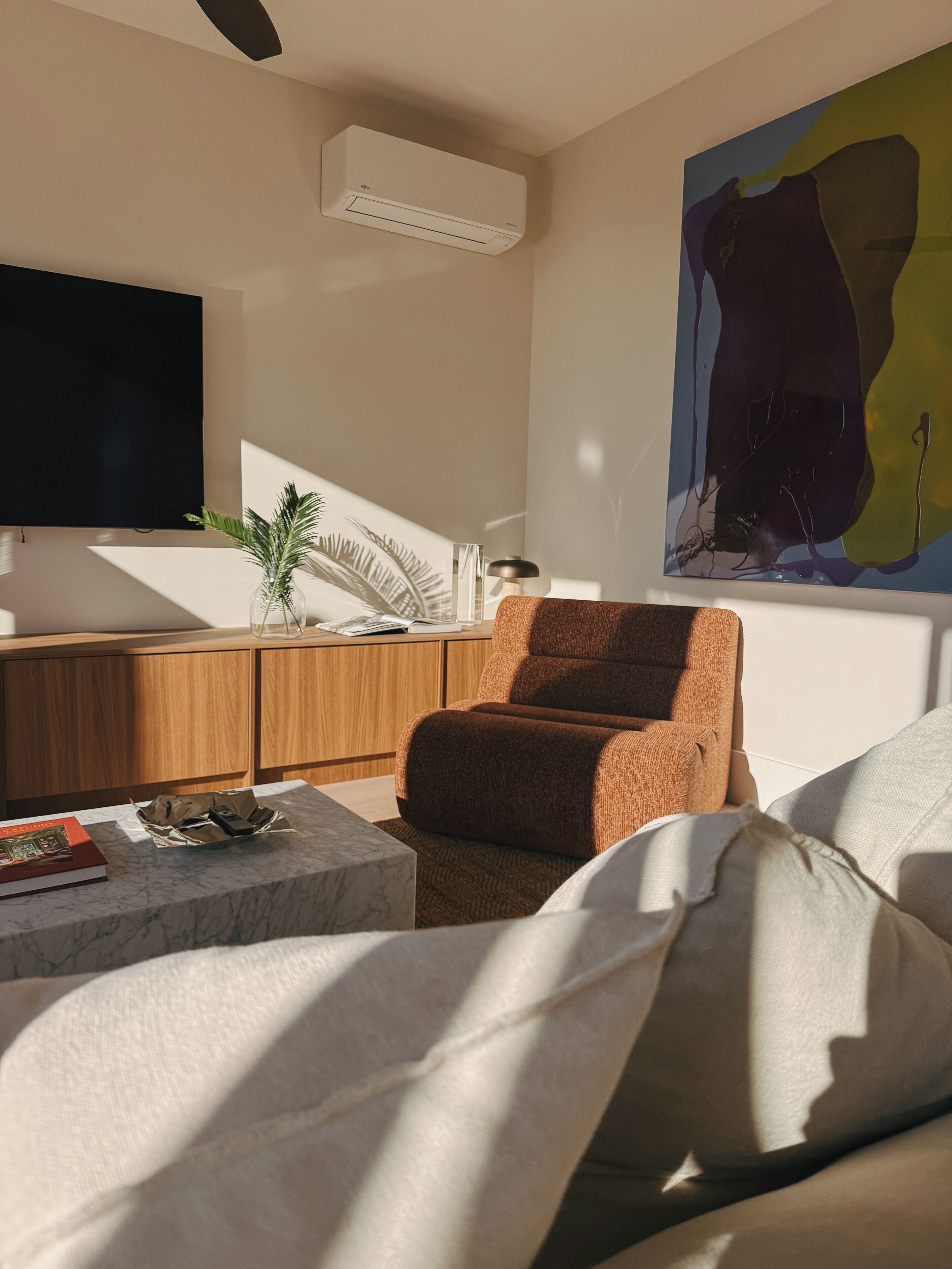 Una sala de estar moderna con un sofá, una mesa de centro, un televisor y un cuadro en la pared.