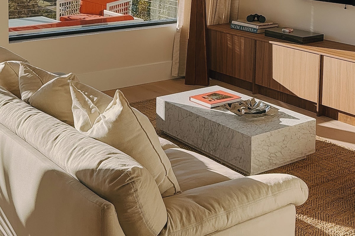 Ein modernes Wohnzimmer mit großem Fenster, Flachbildfernseher, Sofa, Couchtisch und Lampe.