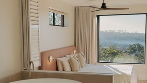 A modern bedroom with a large bathtub, a bed with a view, and a ceiling fan. - Hillcrest Merimbula (Merimbula)