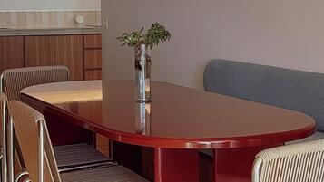 Un comedor con una mesa redonda, seis sillas, una lámpara colgante y una planta pequeña sobre la mesa.
