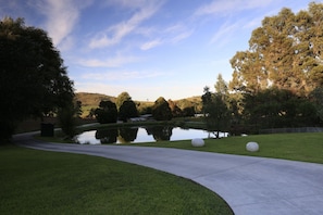 A landscaped area with a pond, pathway, and trees. - De'Vine Escape (Dixons Creek)