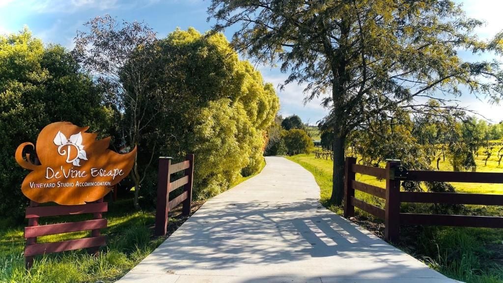 Un sendero conduce a una propiedad llamada DeVine Escape, con un letrero que indica que se trata de un estudio tipo viñedo.