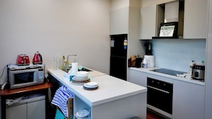 A compact kitchen with a microwave, toaster, sink, and a sign encouraging cleanliness. - De'Vine Escape (Dixons Creek)