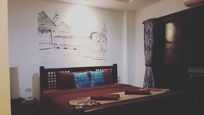 A bedroom with a bed, a wall mural, a desk, and a chair.