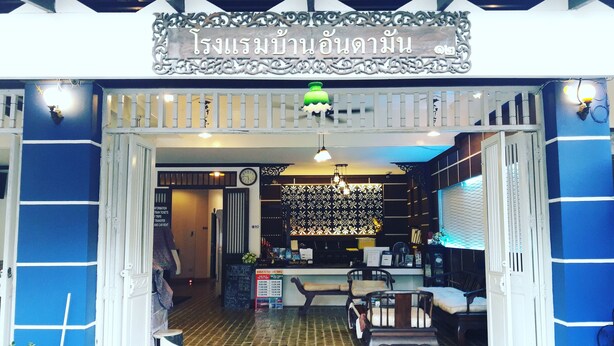 A Thai restaurant entrance with a sign, a clock, and a seating area with a table and chairs.