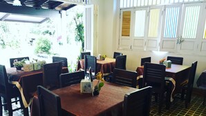 A dining area with tables and chairs, a tiled floor, and a window with blinds.