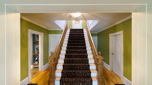 A staircase with wooden balusters and a patterned carpet, leading to a landing with a chandelier. - L'Auberge Gabrièle Inn (Shediac)