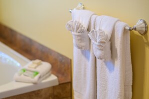 A bathroom with a white bathtub, a towel rack with two towels, and a soap dish.