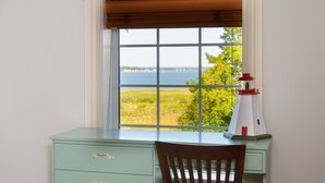 A desk with a view of the sea through a window with a white frame and brown blinds. - L'Auberge Gabrièle Inn (Shediac)