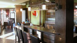A bar area with a counter, stools, and hanging lights. - L'Auberge Gabrièle Inn (Shediac)