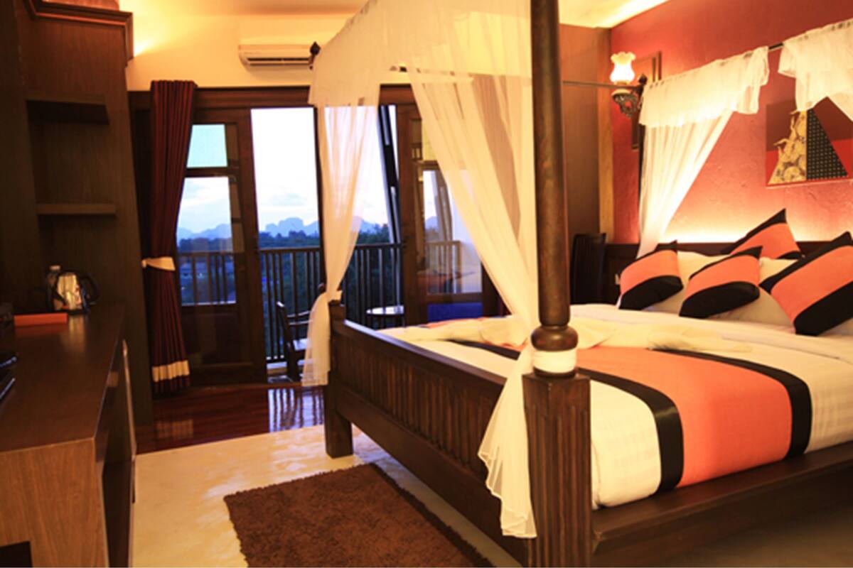 Quarto com cama de dossel, varanda e vista para as montanhas.