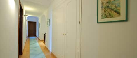 Un pasillo con piso de baldosas, paredes blancas y una puerta al final.