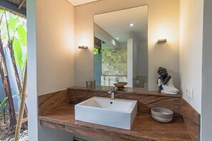 Bathroom features a large sink, mirror, and woven basket on a countertop.