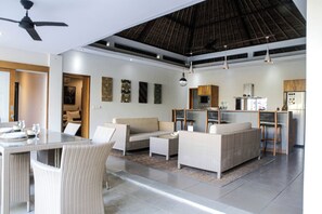 A modern living room with a dining area, a kitchen, and a ceiling fan. - Balinea Holiday Home (Keroboken Kelod)