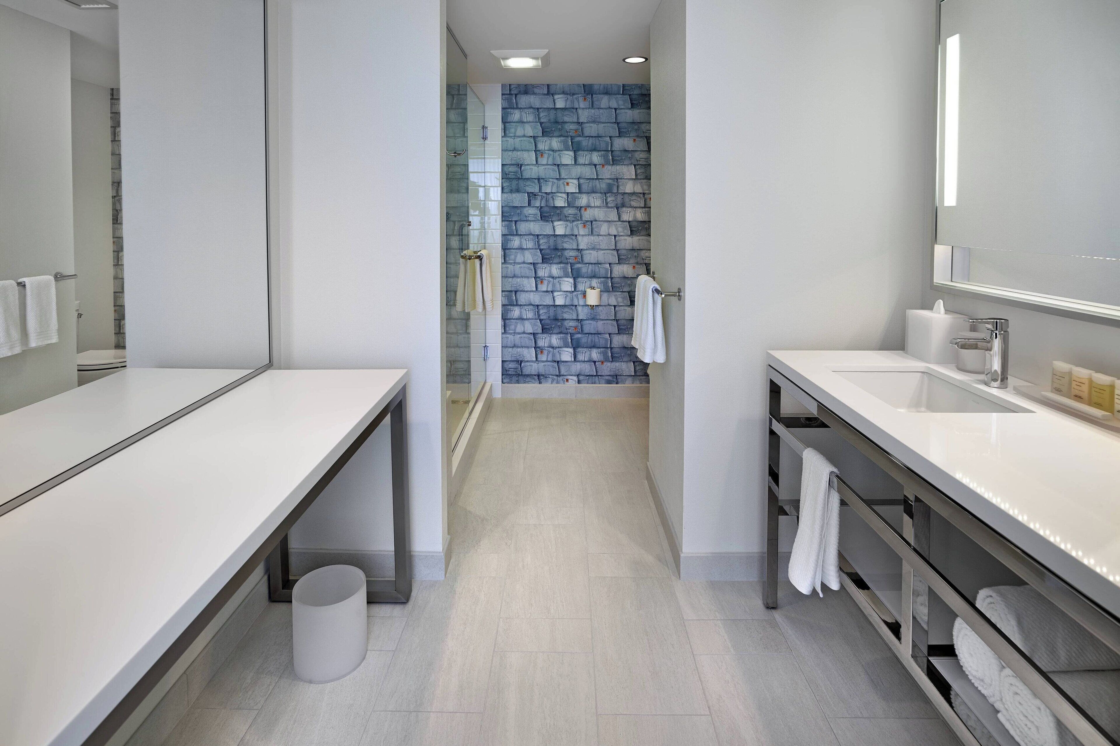 Une salle de bain moderne avec un meuble-lavabo blanc, une cabine de douche en verre et un mur bleu à texture.