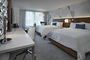 A hotel room with two beds, a desk, a TV, and a modern geometric wall design. - Renaissance Edmonton Airport Hotel (Edmonton International Airport)