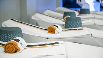 Neatly arranged towels and bathrobes on a hotel room's bed.