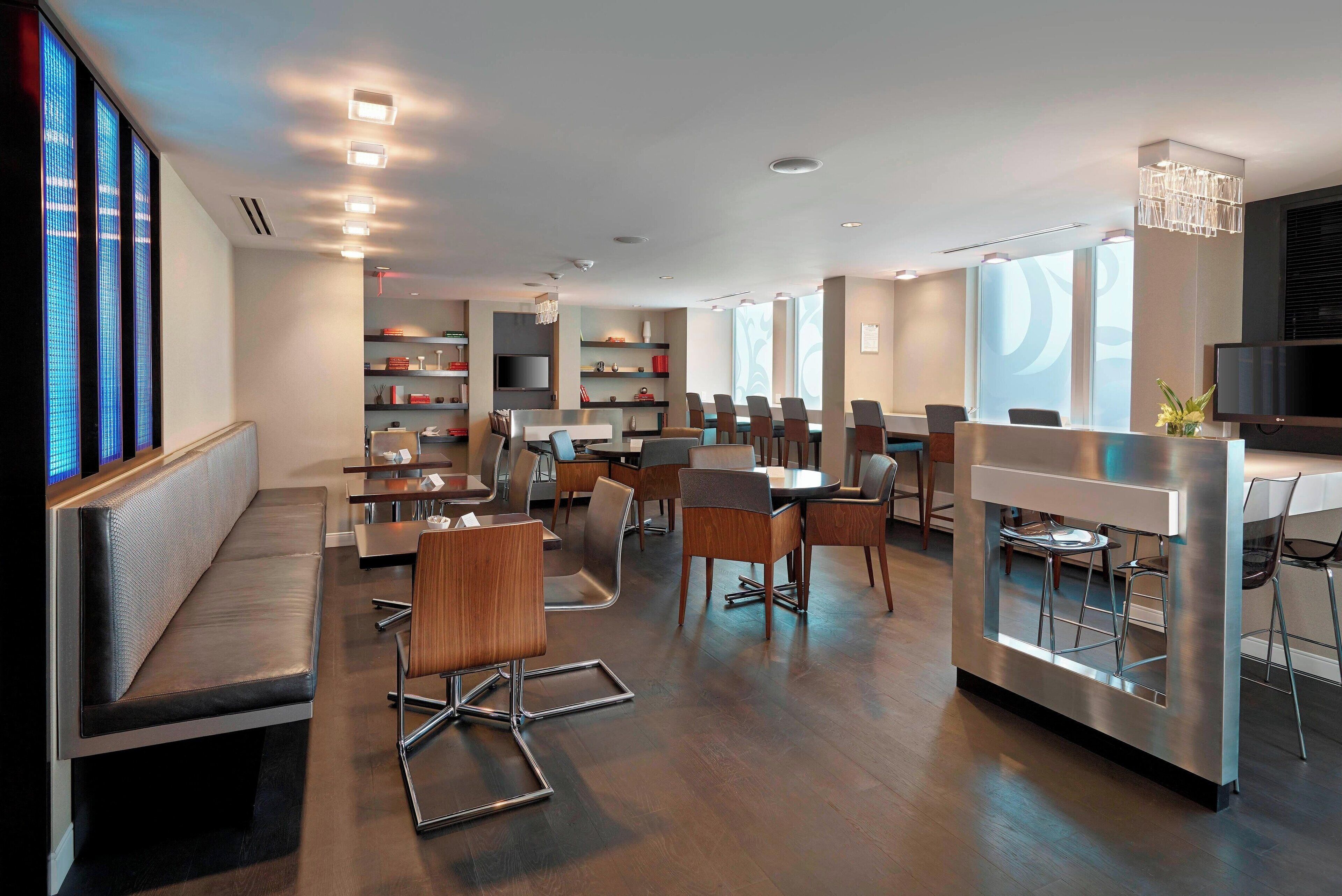 Een moderne hotelentree met een receptiebalie, een zithoek en een eetgedeelte.