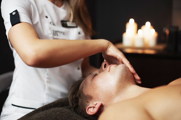 A person receiving a head massage in a room with candles in the background. - Gwiazda Morza Resort SPA&SPORT (Wladyslawowo)