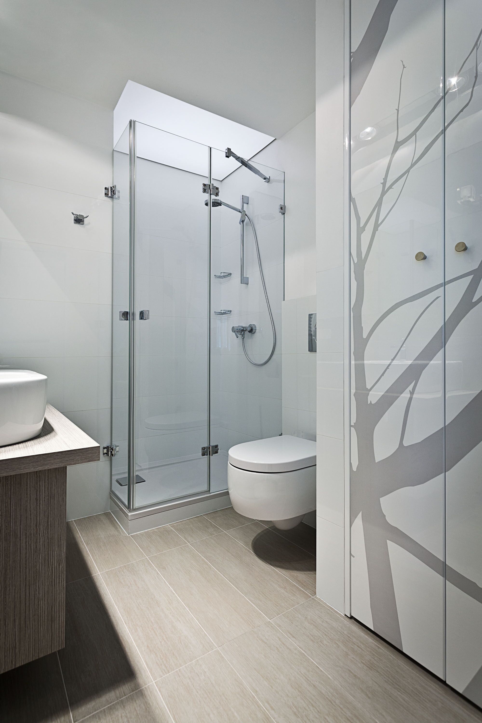 A modern bathroom with a glass-enclosed shower, a toilet, and a vanity with a wooden countertop.