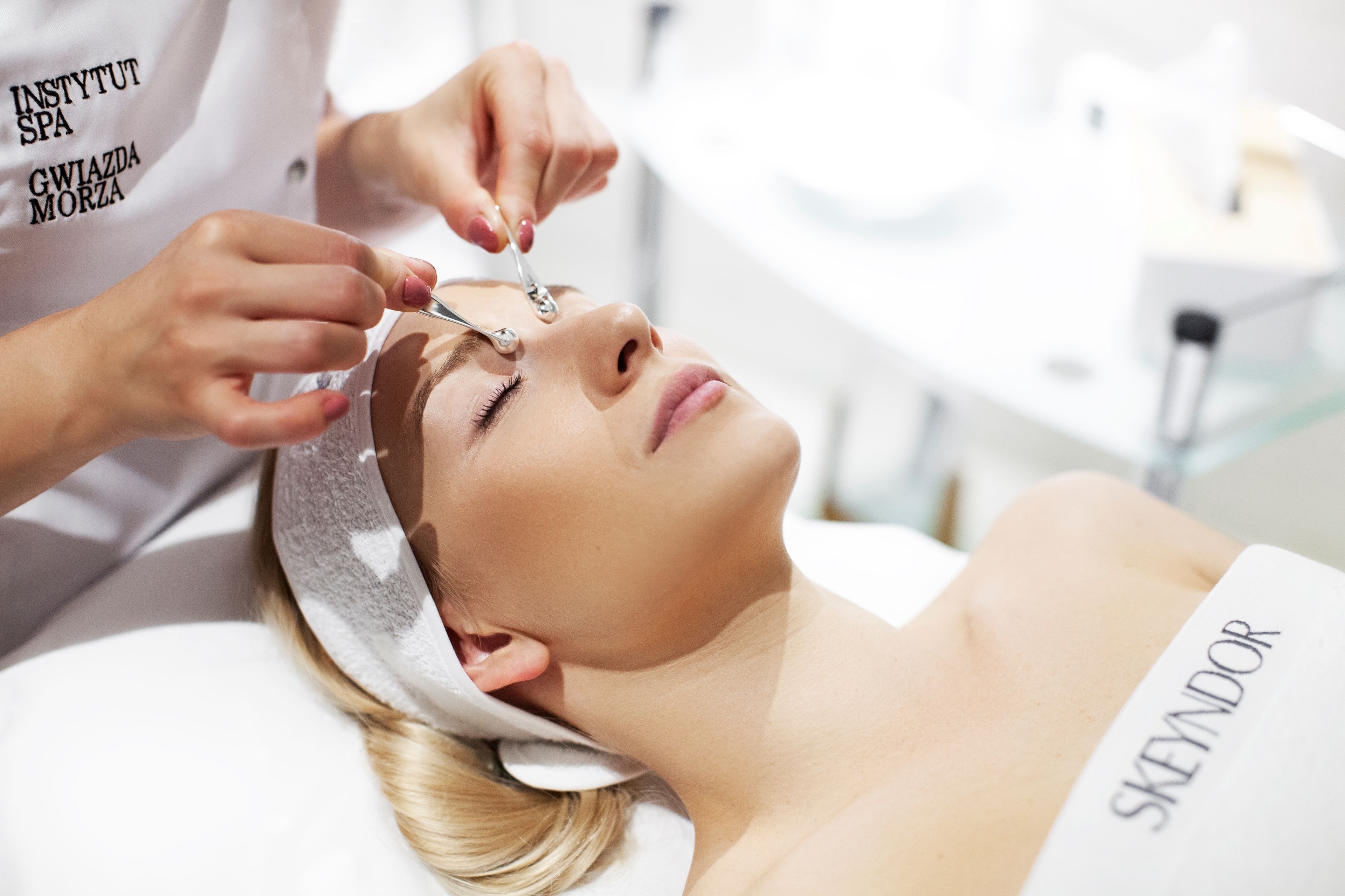 A person receiving a facial treatment in a clinical setting.