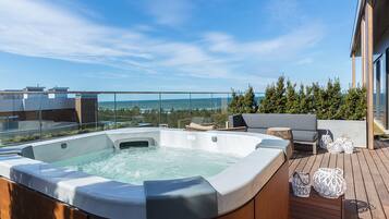 Une terrasse sur le toit avec un jacuzzi, un espace salon et une vue sur l’océan.