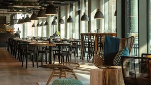 A spacious restaurant with high ceilings, pendant lighting, and large windows.