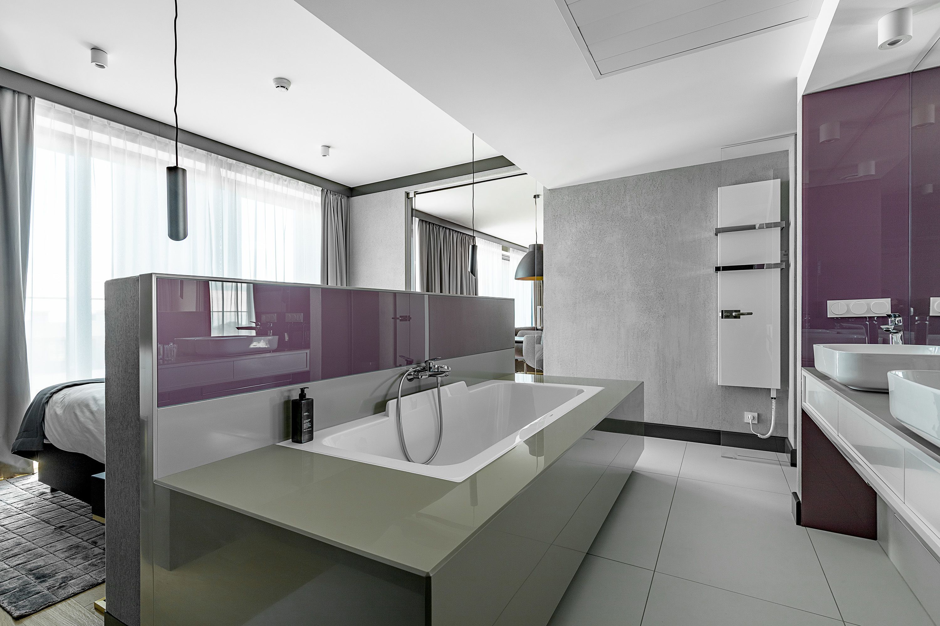 A modern bathroom with a large bathtub, a vanity with a mirror, and a separate sink area.