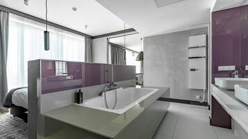 A modern bathroom with a large bathtub, a vanity with a mirror, and a separate sink area.